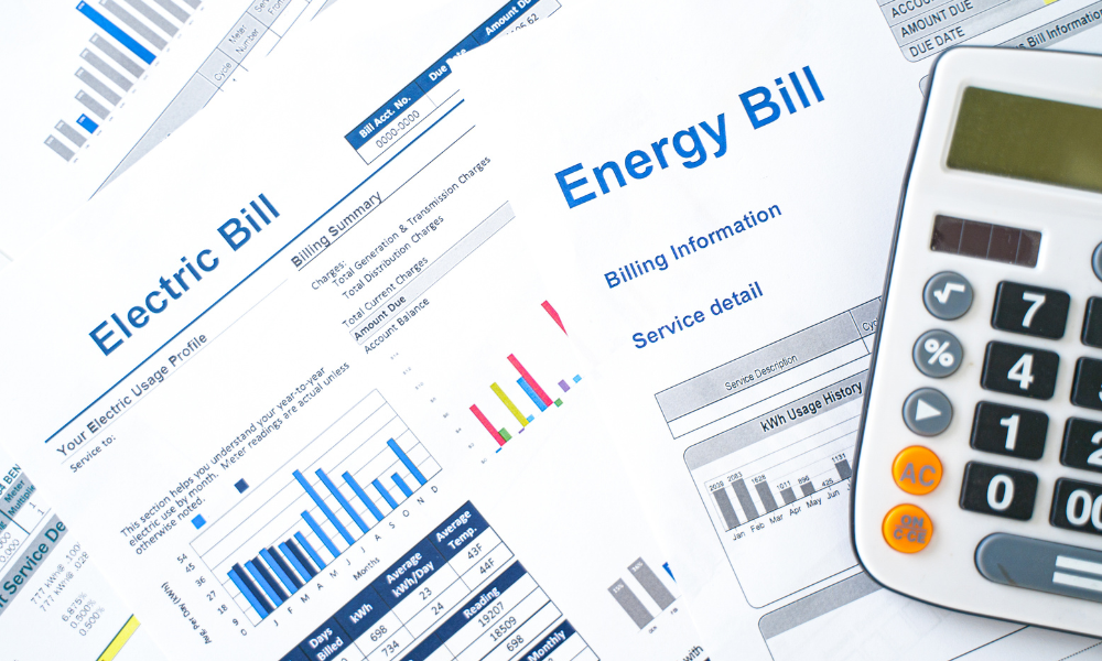 Electric and energy bills with a calculator, showing how to lower utility costs after going solar with Sun Energy Today.