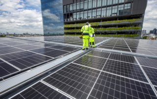 Commercial rooftop solar installation with technicians on office building showcasing energy savings ROI and business growth benefits of solar power in 2026